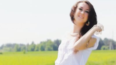 Nature loving girl wearing heels poses in a grassy summer field