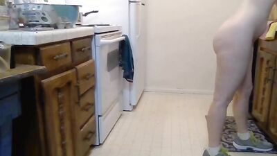 Naked housewife with a mask is preparing some food in the kitchen