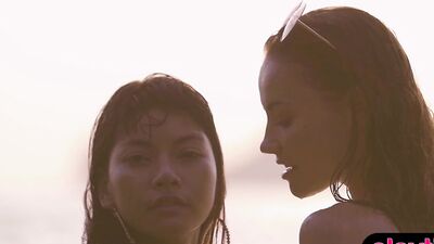 Two alluring girls are posing naked outdoors at a beach