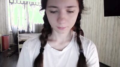 Teen girl with pigtails is on the phone while gently rubbing her pussy